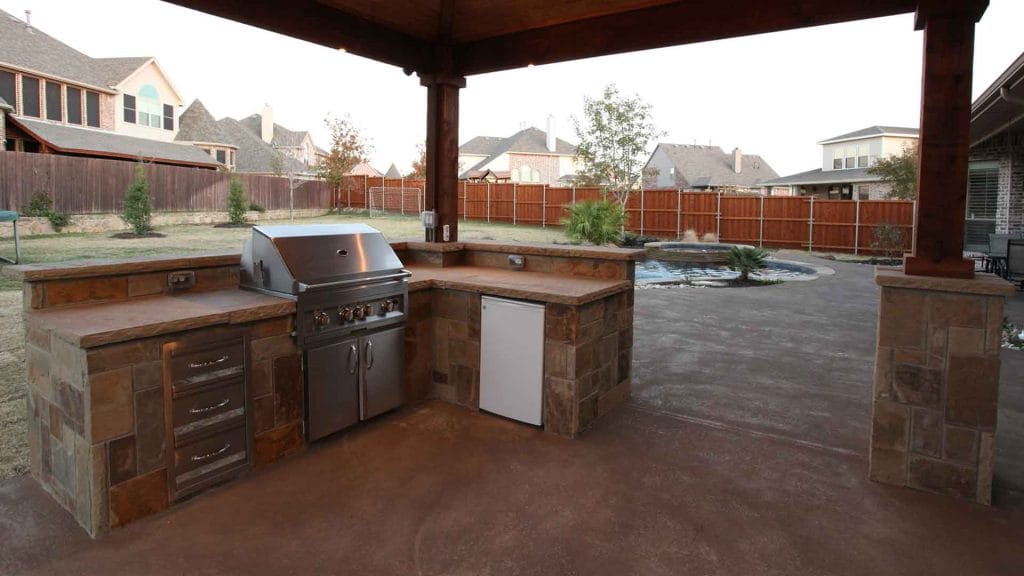 Covered outdoor kitchen with a built-in grill, counters and storage