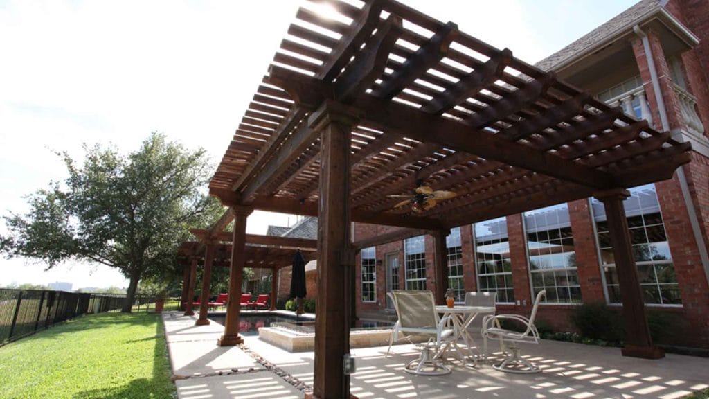 Wood pergola beside a brick home with an outdoor seating area