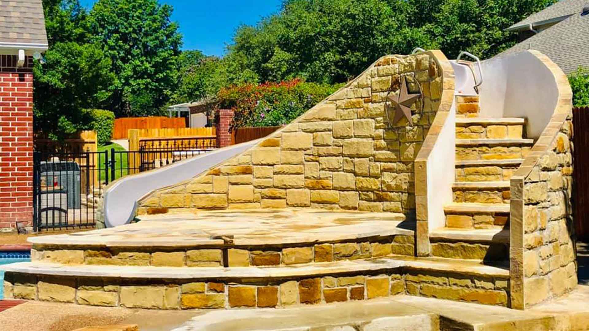 Resort Style Pool Slide Stone Masonry Deck Built for Texas Backyards